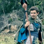 Gracz w średniowiecznym stroju z kostiumu RPG trzyma laskę w lesie